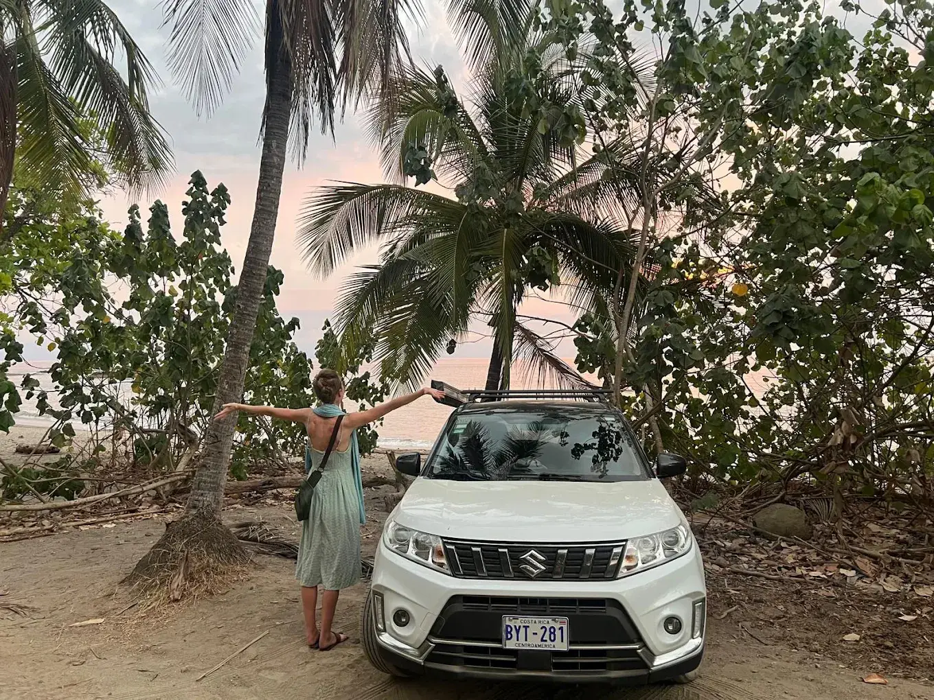 Traveler beside a white SUV near the beach in Costa Rica